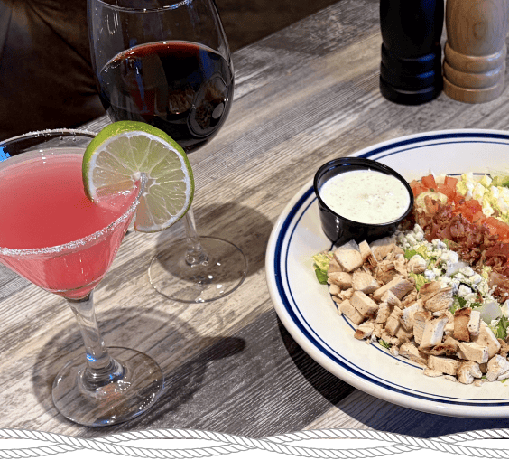 cobb salad with a glass of wine and pink cocktail, courtesy of the Crafty Buffalo